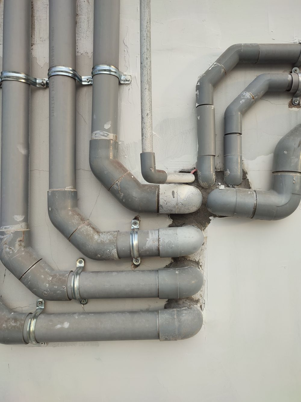 Run of grey plastic waste pipes along a wall