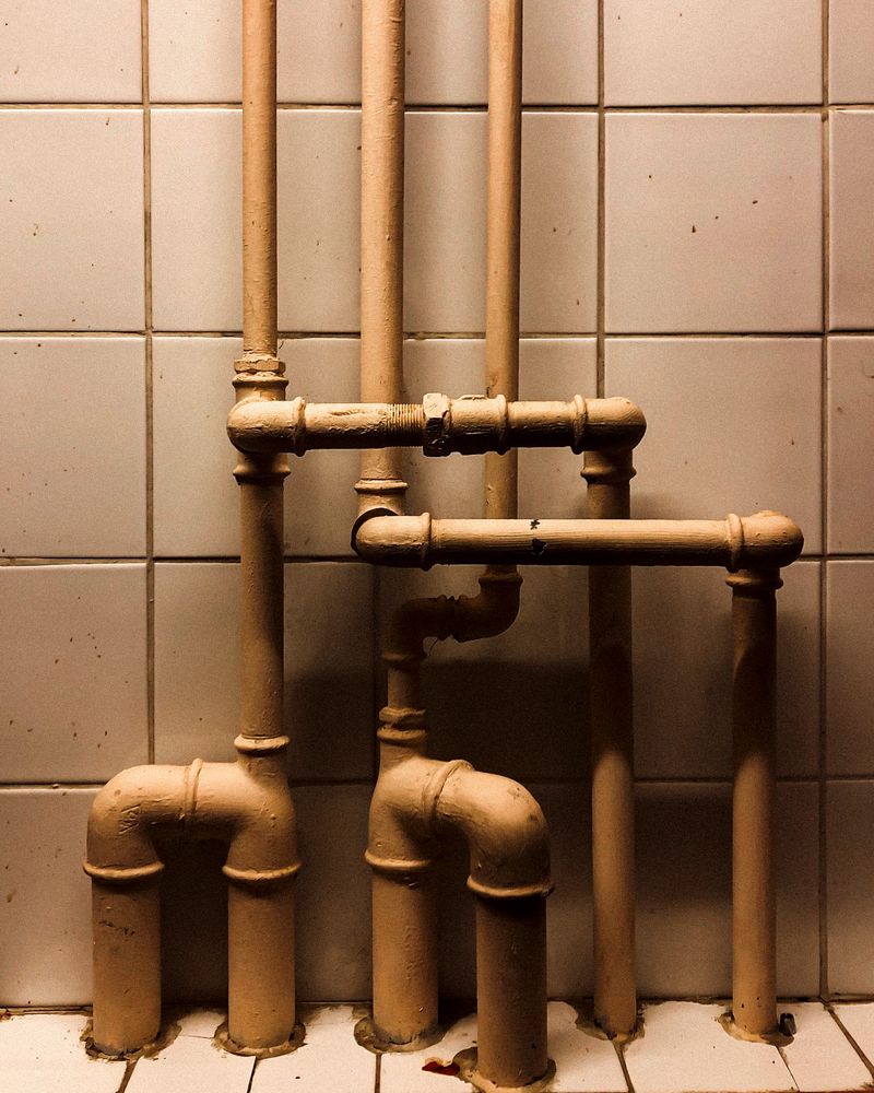 Copper pipework and elbows running across tiled wall