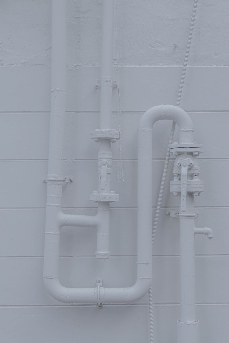 Painted white pipe run against a plain wall